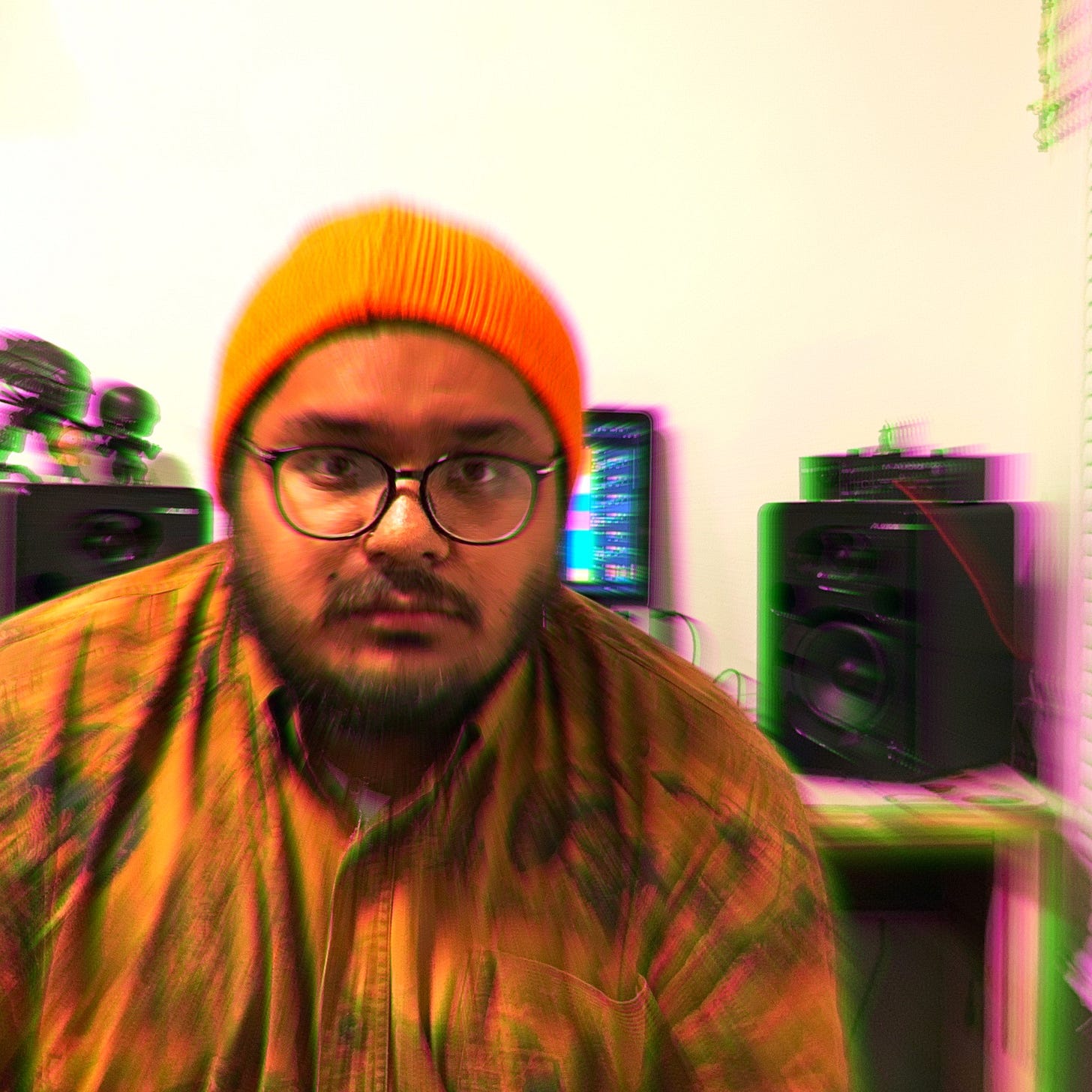 A blurry picture of a man in front of a computer and some speakers