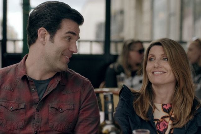 A close up of Rob Delaney and Sharon Horgan sitting next to each other and laughing.
