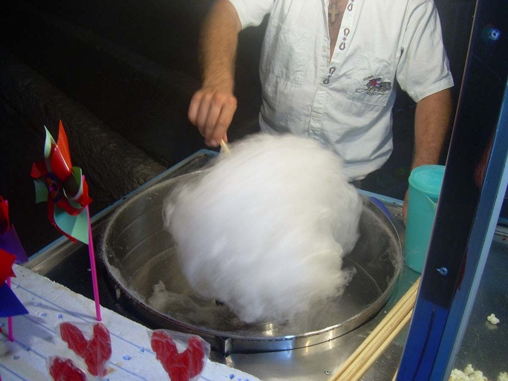 Cotton candy being made on an electric cotton candy machine.
