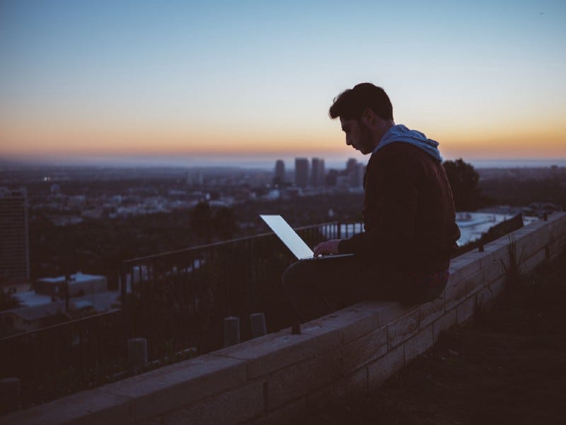 A man siting on the terrace with a laptop