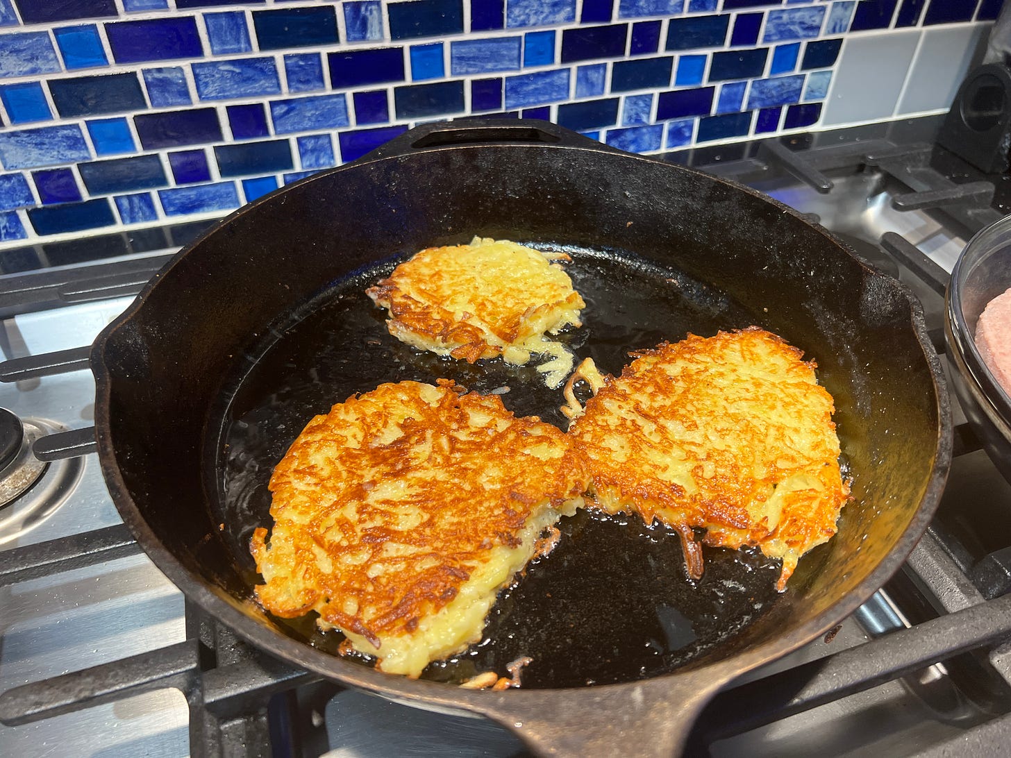 Latkes frying in a cast iron pan