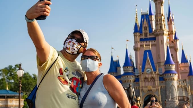 In this handout photo provided by Walt Disney World Resort, guests stop to take a selfie at Magic Kingdom Park at Walt Disney World Resort on July 11, 2020 in Lake Buena Vista, Florida. July 11, 2020 is the first day of the phased reopening.