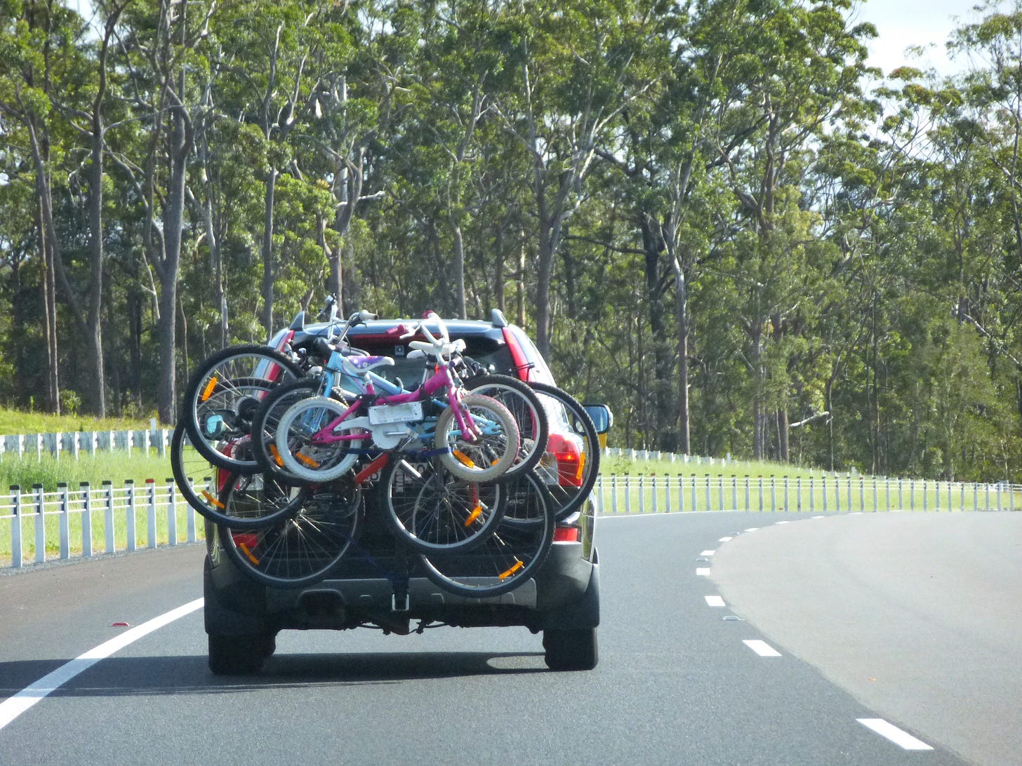 A car driving along a road, with several bicycles attached to the back