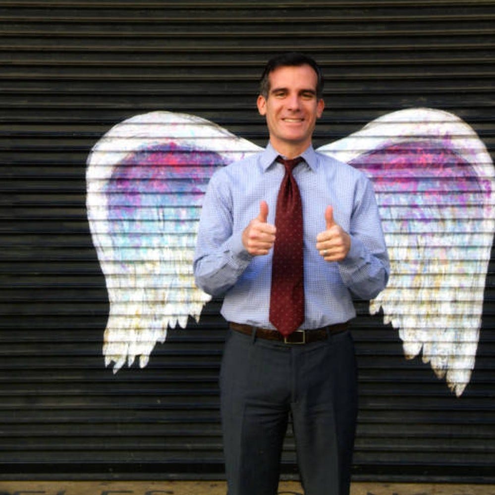 Mayor Eric Garcetti giving a "thumbs up" and posing in front of a mural  depicting angel wings — Calisphere