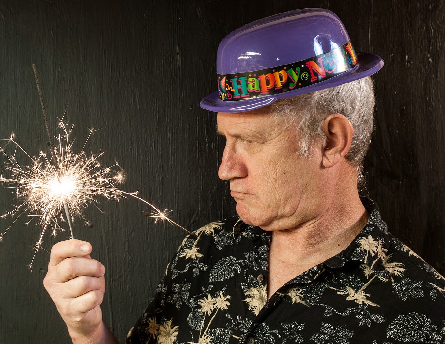 John holding sparkler while wearing a silly New Years Hat