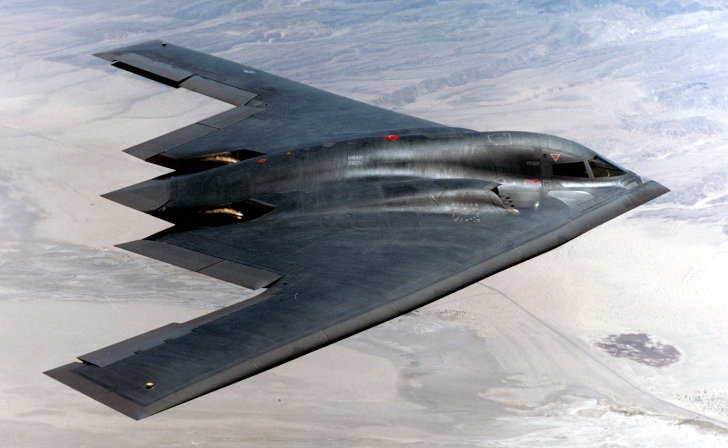 A Northrop Grumman B-2 Spirit, flying high over the desert