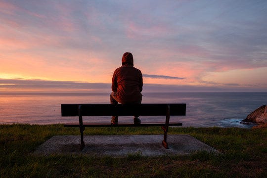 Lonely man sits alone on the rocky coast and enjoying sunset. View over  rocky cliff to ocean horizon Stock Photo | Adobe Stock