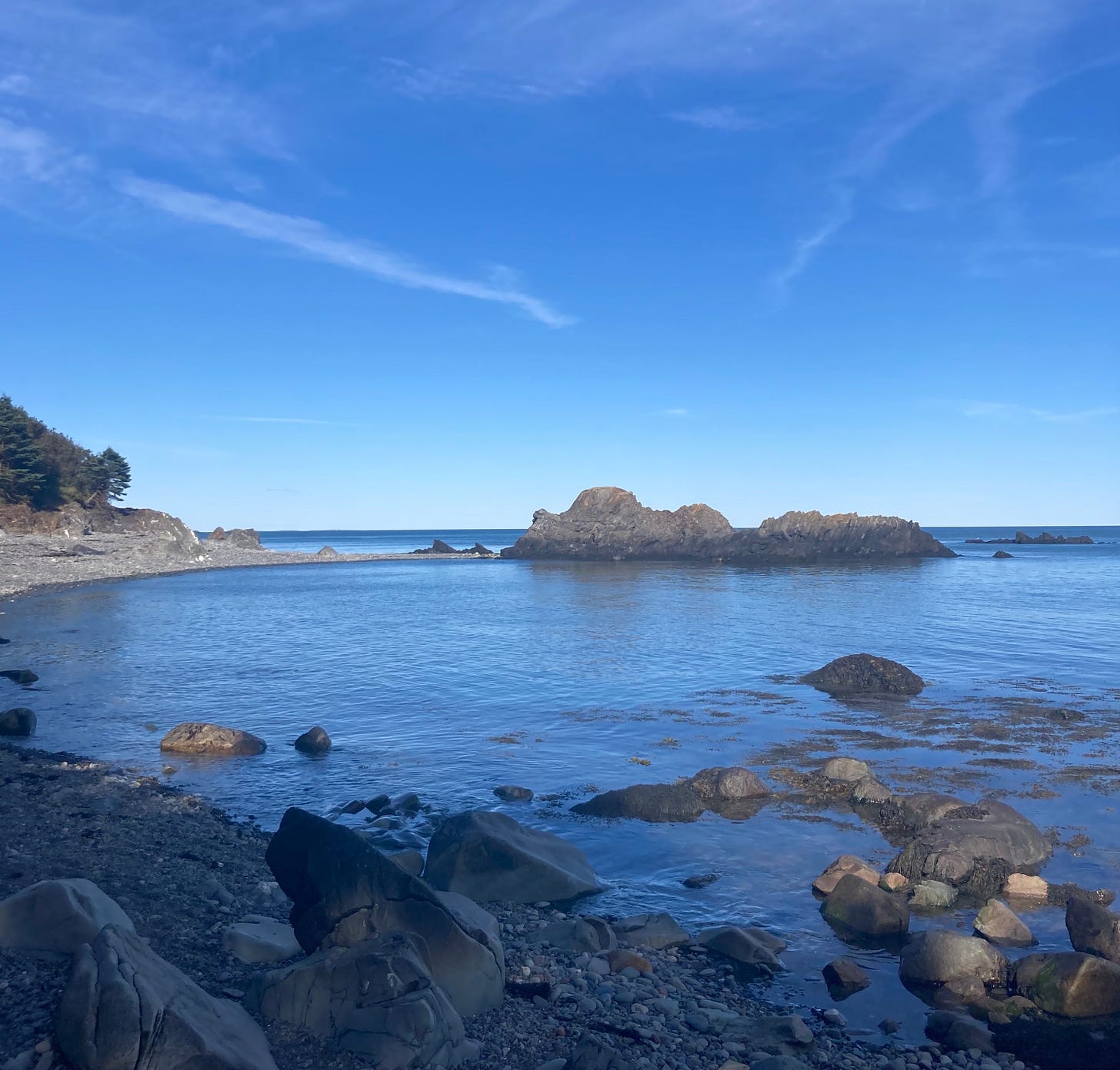 A rocky cove with blue water and blue sky