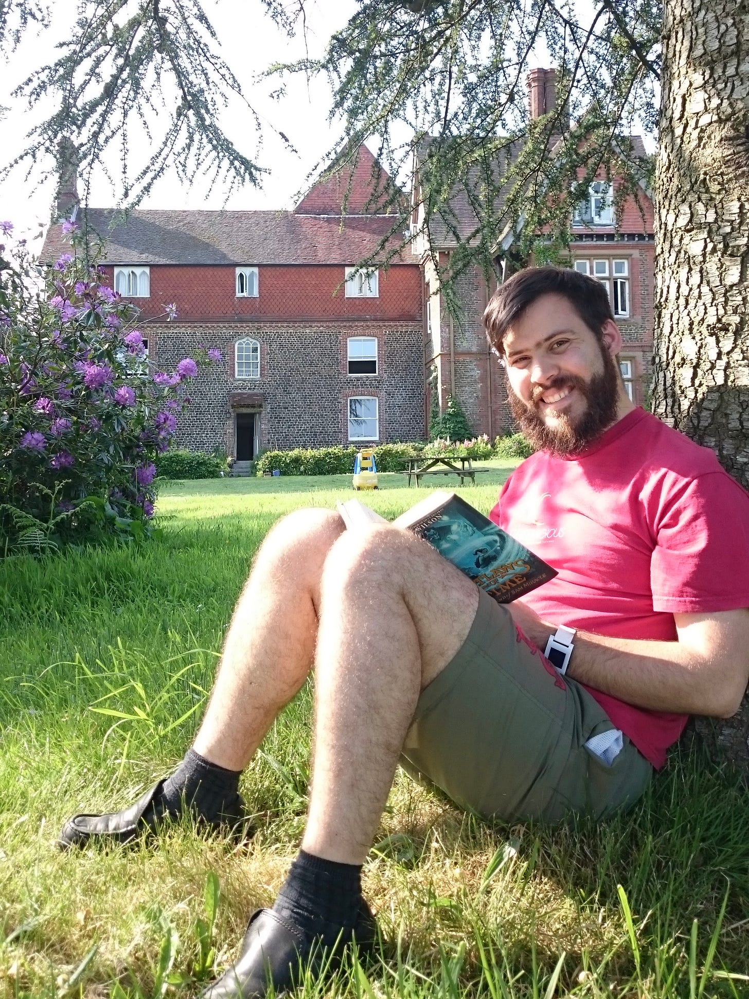 I'm sitting under a tree reading a book, with the historic Manor House that homes L'Abri Fellowship in the background.