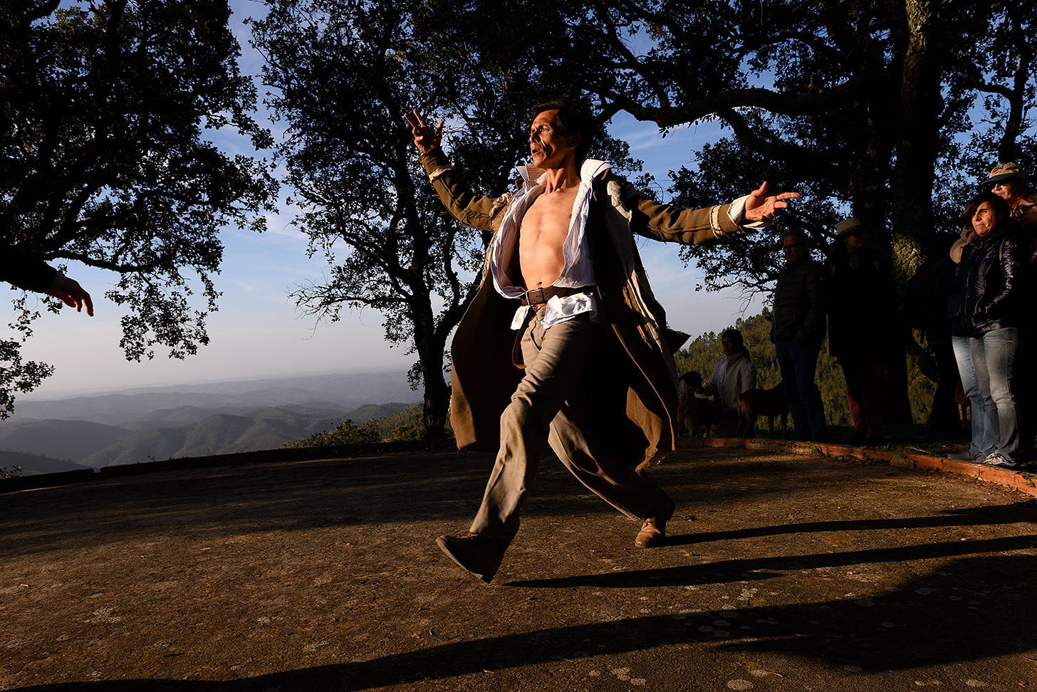 Dancer in spectacular Portuguese mountain setting watched by audience members.