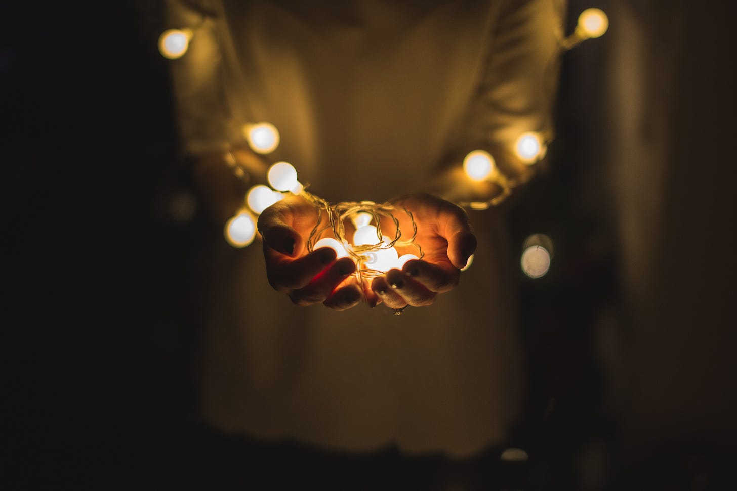 hands holding illuminated string lights