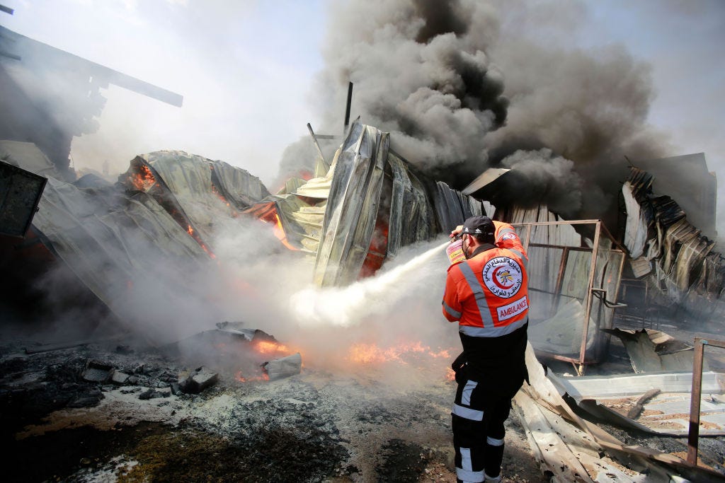 A Palestinian firefighter puts out a fire at a sponge factory after it was hit by Israeli artillery shells. (Ahmed Zakot / Getty Images) A Palestinian firefighter puts out a fire at a sponge factory after it was hit by Israeli artillery shells. (Ahmed Zakot / Getty Images)