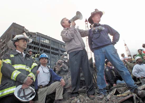 Original caption: U.S. President George W. Bush addresses a crowd as he stands with retired firefighter Bob Beckwith (R) from Ladder 117 at the scene of the World Trade Center disaster in New York, September 14, 2001. The World Trade Center Towers and 7 World Trade Center were destroyed after both the landmark towers were struck by two hijacked planes in a terror attack on September 11.  REUTERS/Win McNamee September 14, 2001