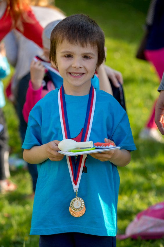 Pre-schooler holding a medal and prizes