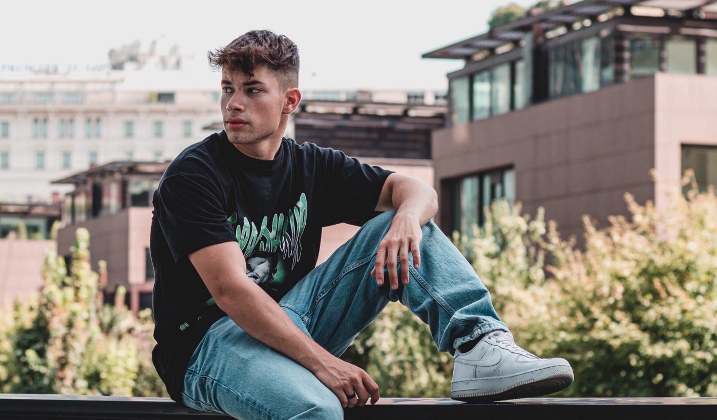 Handsome young man sitting on a railing overlooking an urban scenery