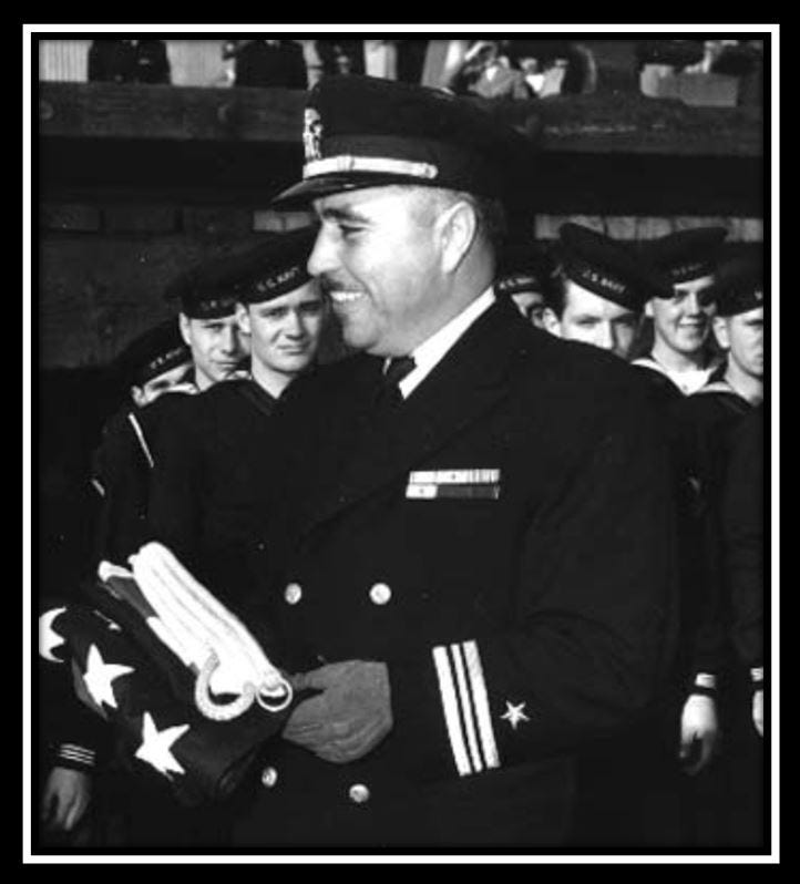 Candid shot of Evans aboard his ship. He is in uniform, looking to someone off camera, and smiling.