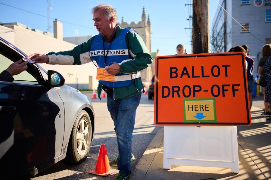 An official ballot collector for the Cuyahoga County Board of Elections gives a voter their "I Voted" sticker after depositing their mail-in ballots into a collection box in Cleveland, Ohio on November 6, 2022, ahead of the midterm elections.
