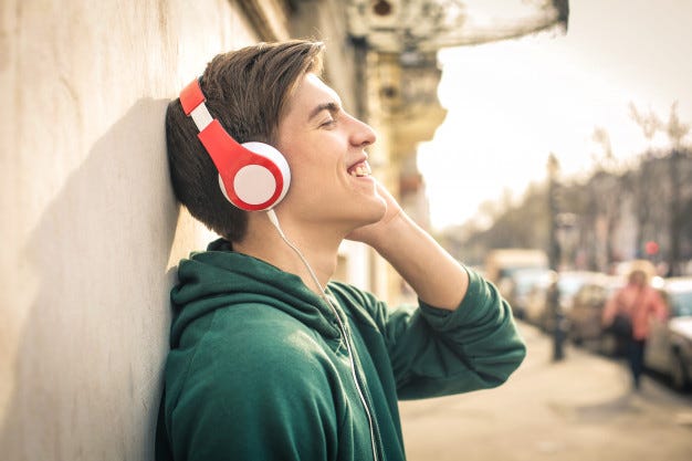 Teenager standing in the street, listening music with headphones Premium Photo