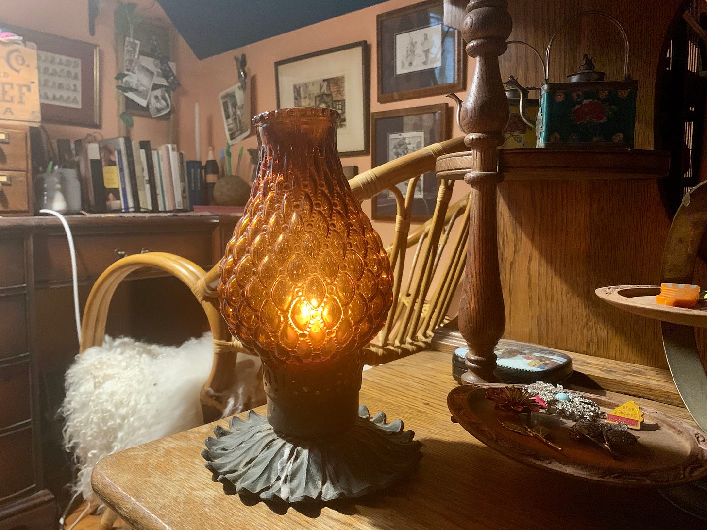 an amber glass lantern with a candle inside on a wood bureau