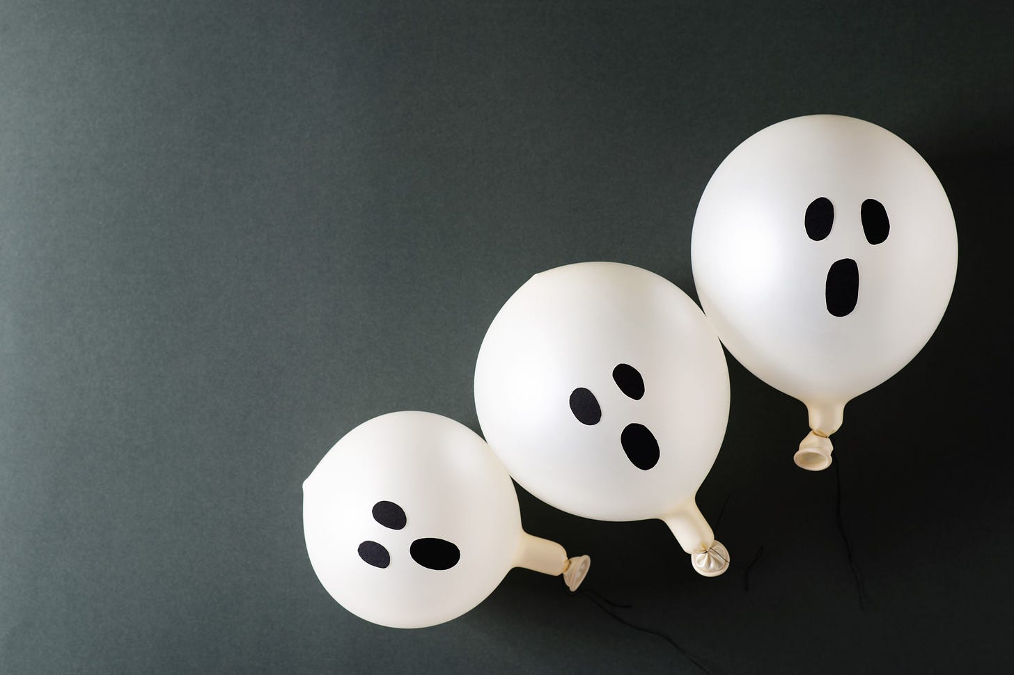 Three small ghost balloons sit clustered together from smallest to largest.