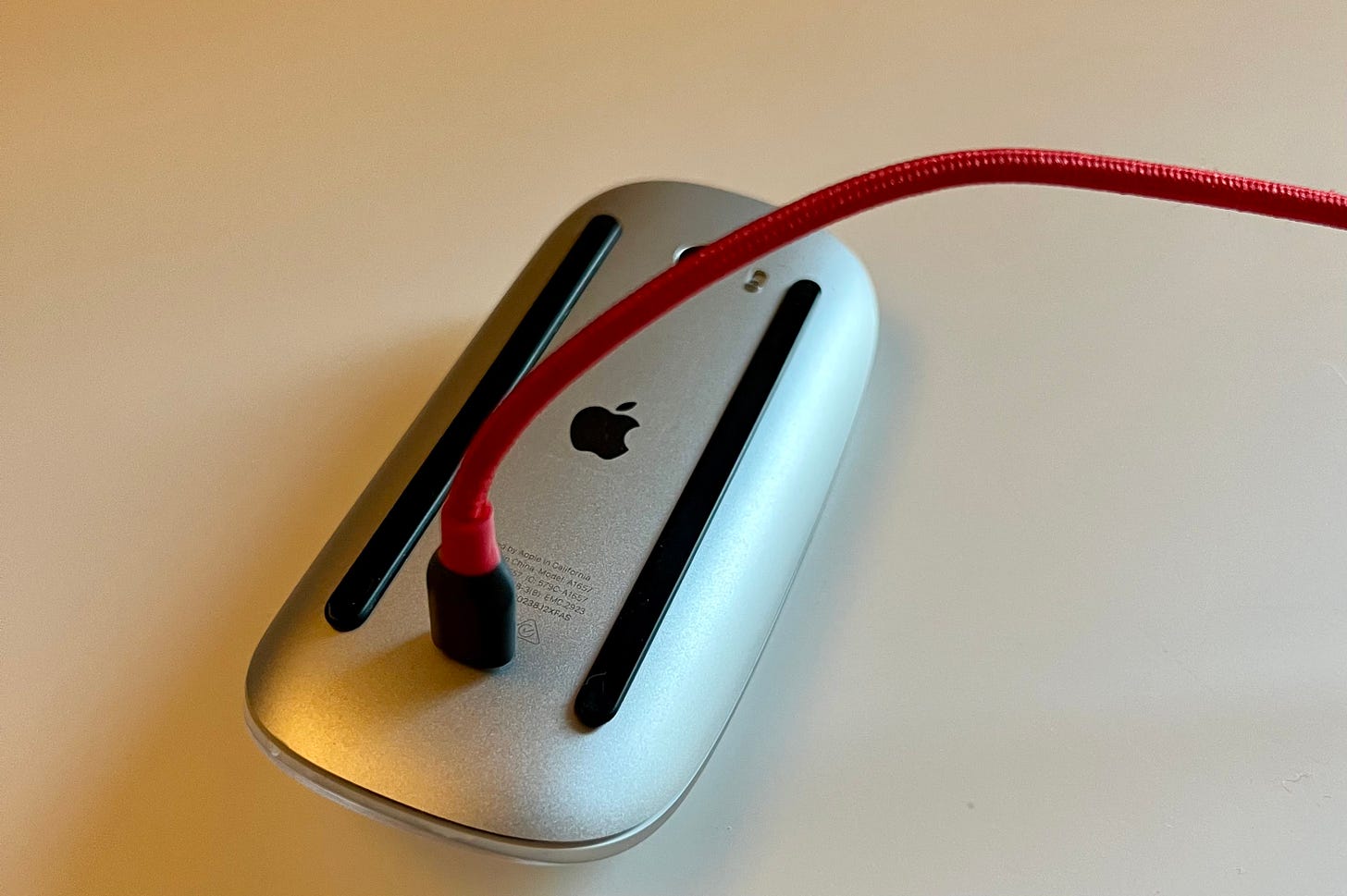 The Magic Mouse flipped over, ready to be charged.
