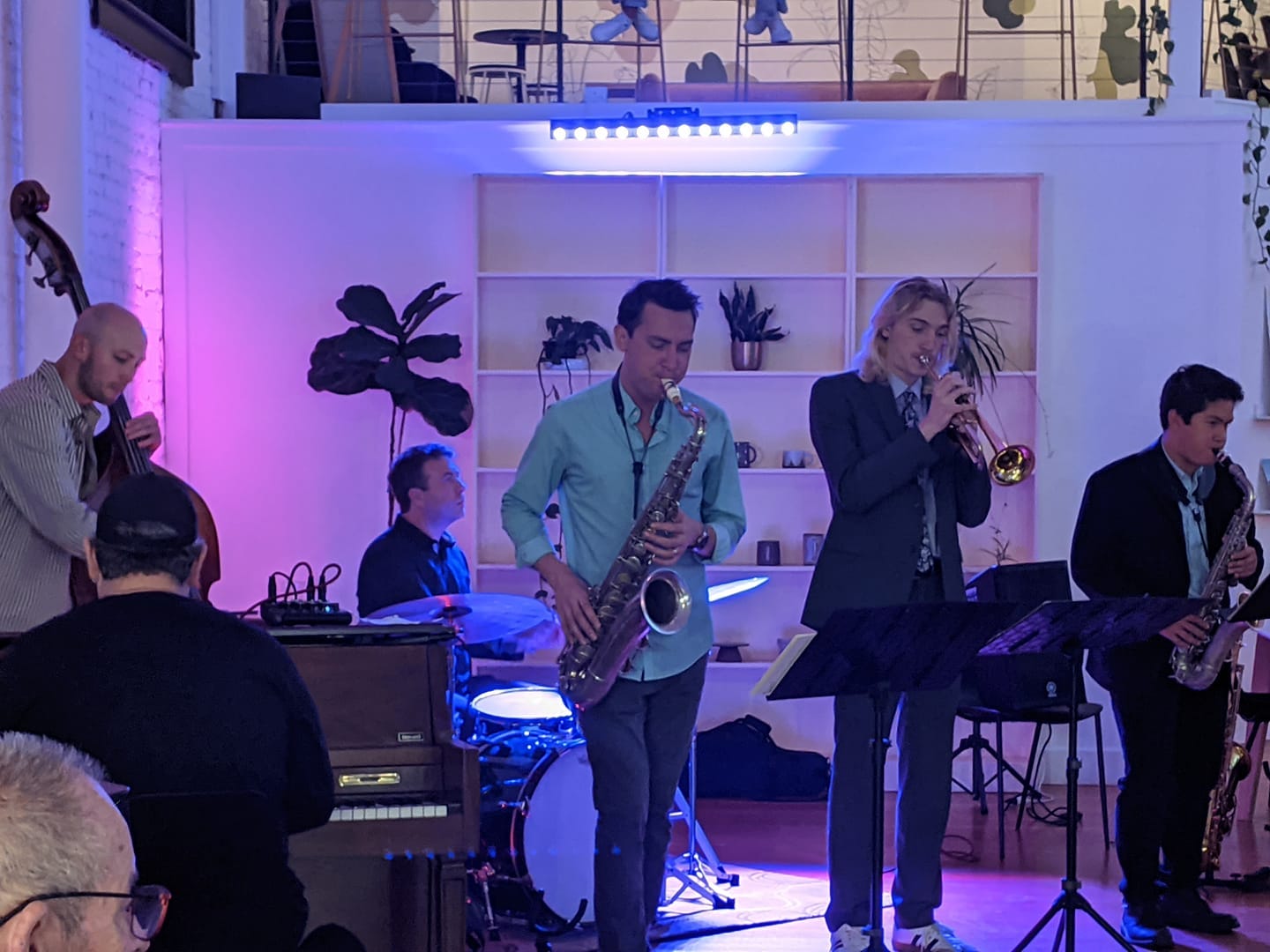 piano, bass, drums, two saxes, and a trumpet, lit by soft purple light