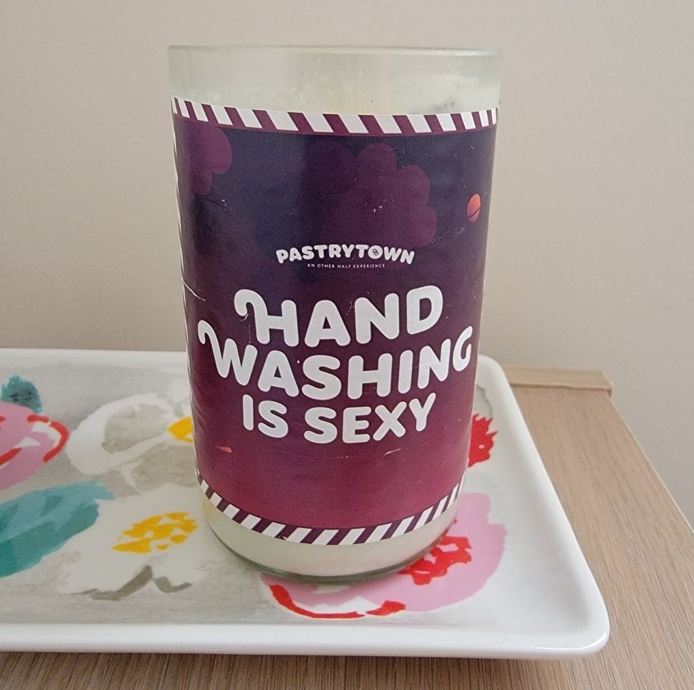 A photo of a sticker on a candle that reads "Hand Washing is Sexy"