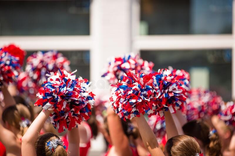 Cheerleaders Waving Red, White, and Blue Pom Poms During Fourth of July Parade.  royalty free stock photo
