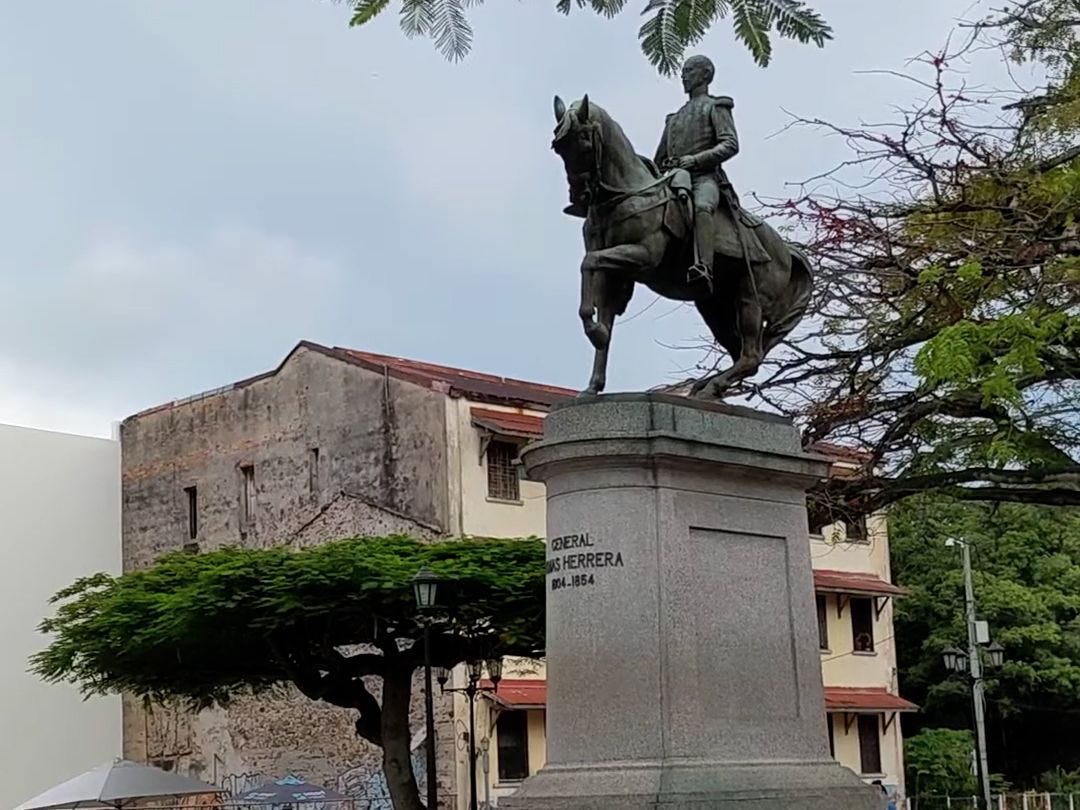 A metal statue of General Tomas Herrera sitting on top of a horse surrounded by Flamboyan trees