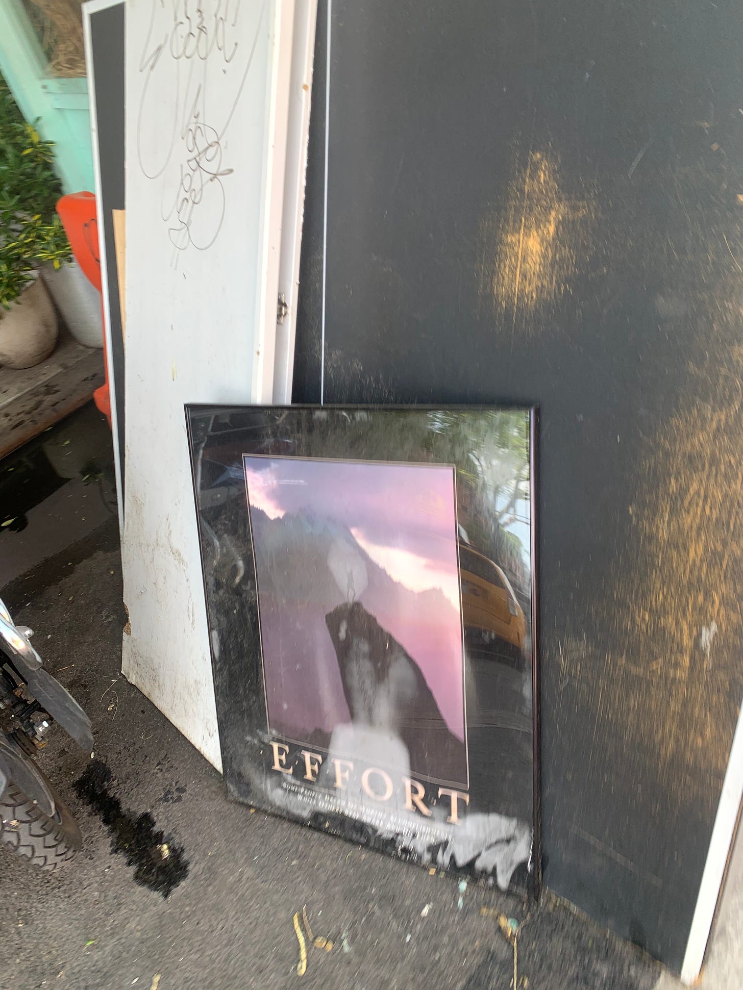 A framed poster reading "effort" stands leaning against a bus stop