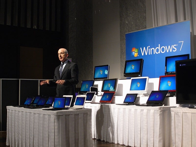 Photo of me in a suit with several rows of Windows 7 PCs on display and a sign that says Windows 7.
