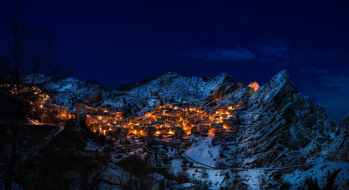 Small town in a mountain valley at night, with every house lit by golden light
