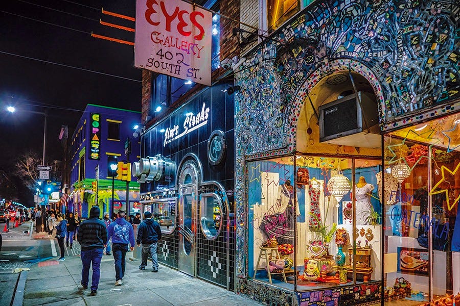 People walking on a street, at night, with lots of colorful shop windows