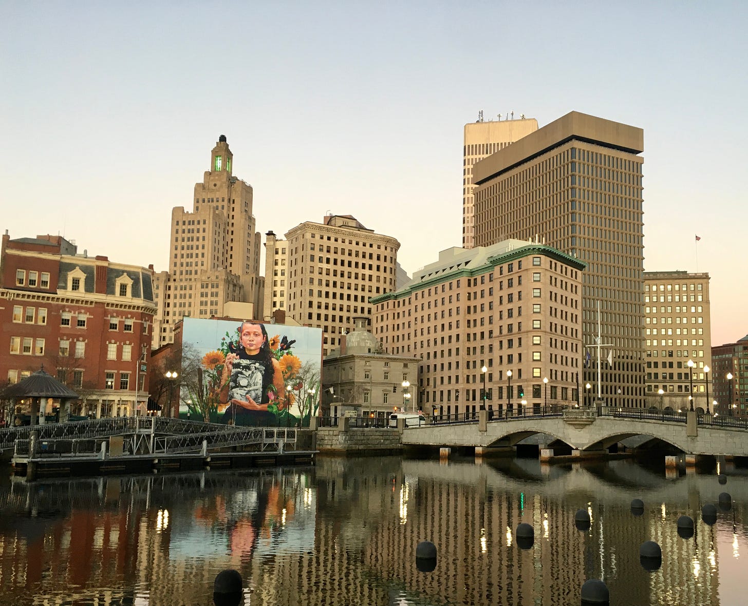 A view of downtown Providence's skyscrapers and office buildings, reflected in the river.