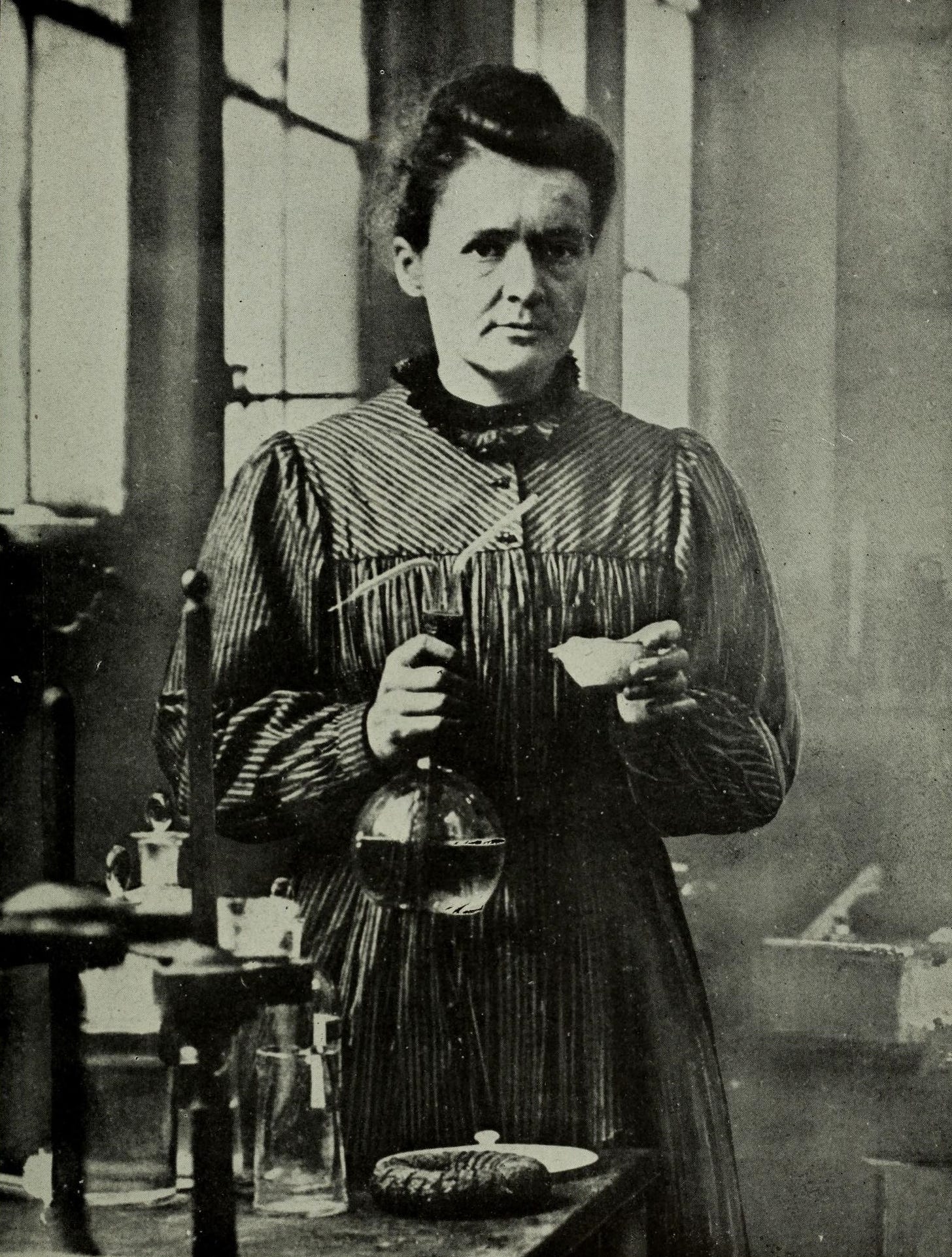 Marie Curie holding beaker.