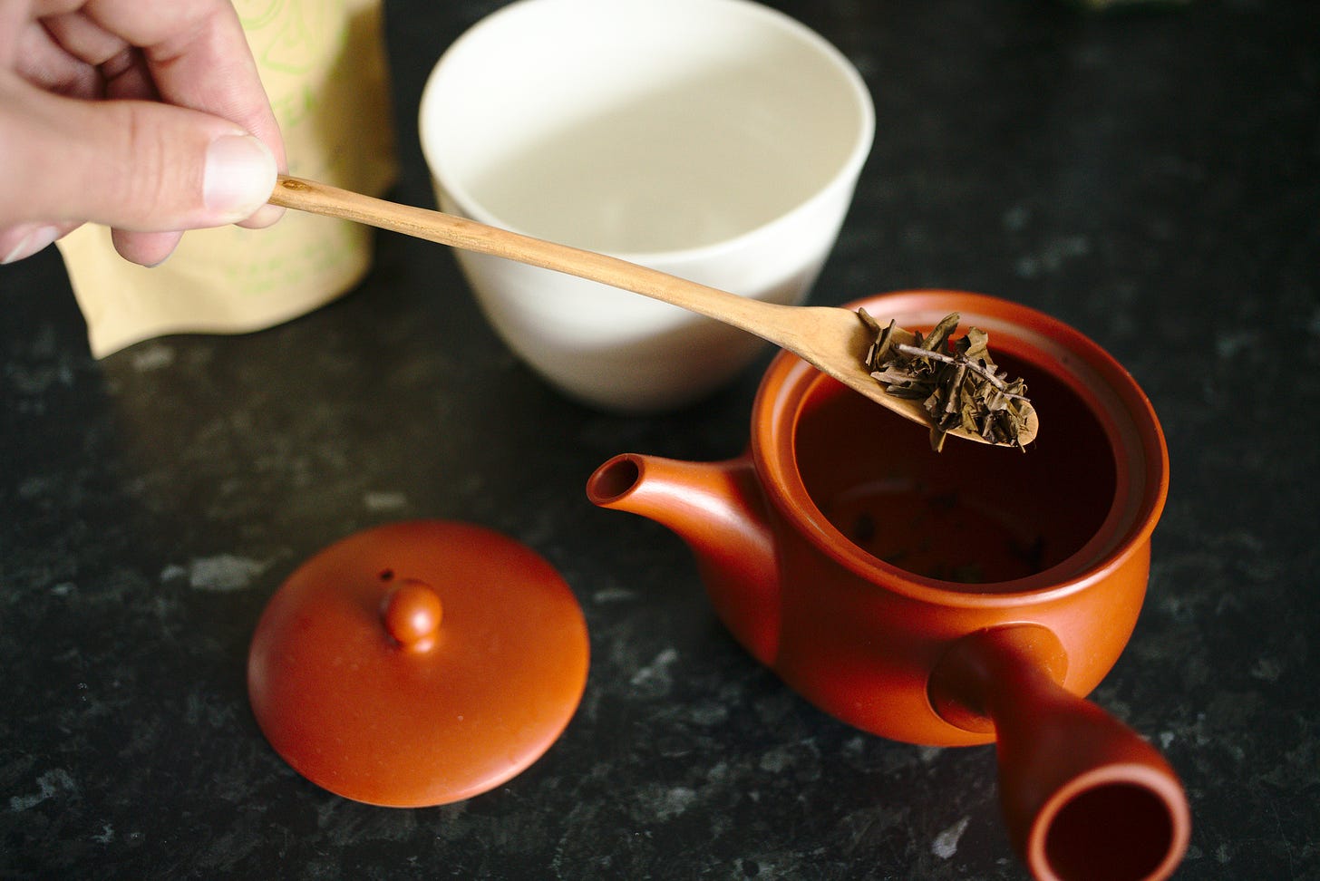 A long cherry tea scoop from our shop, pouring some houjicha tea into our Japanese tea pot.