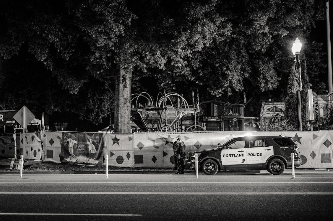 Free Greyscale Photo of Two Policemen Standing Infront of a Parked Police Car  Stock Photo