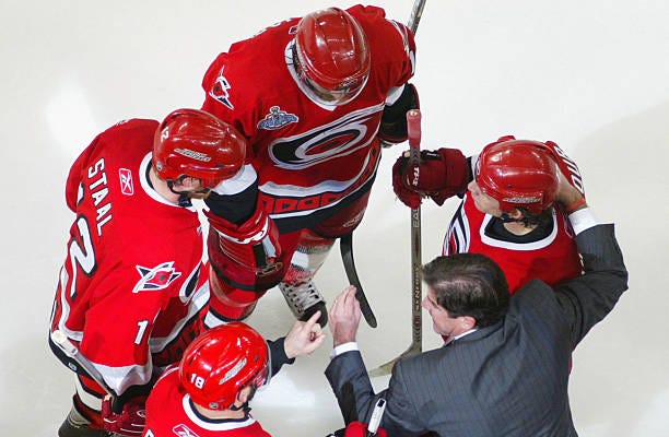 Head coach Peter Laviolette of the Carolina Hurricanes talks with Eric Staal and Rod Brind'Amour during a timeout against the Edmonton Oilers in game...