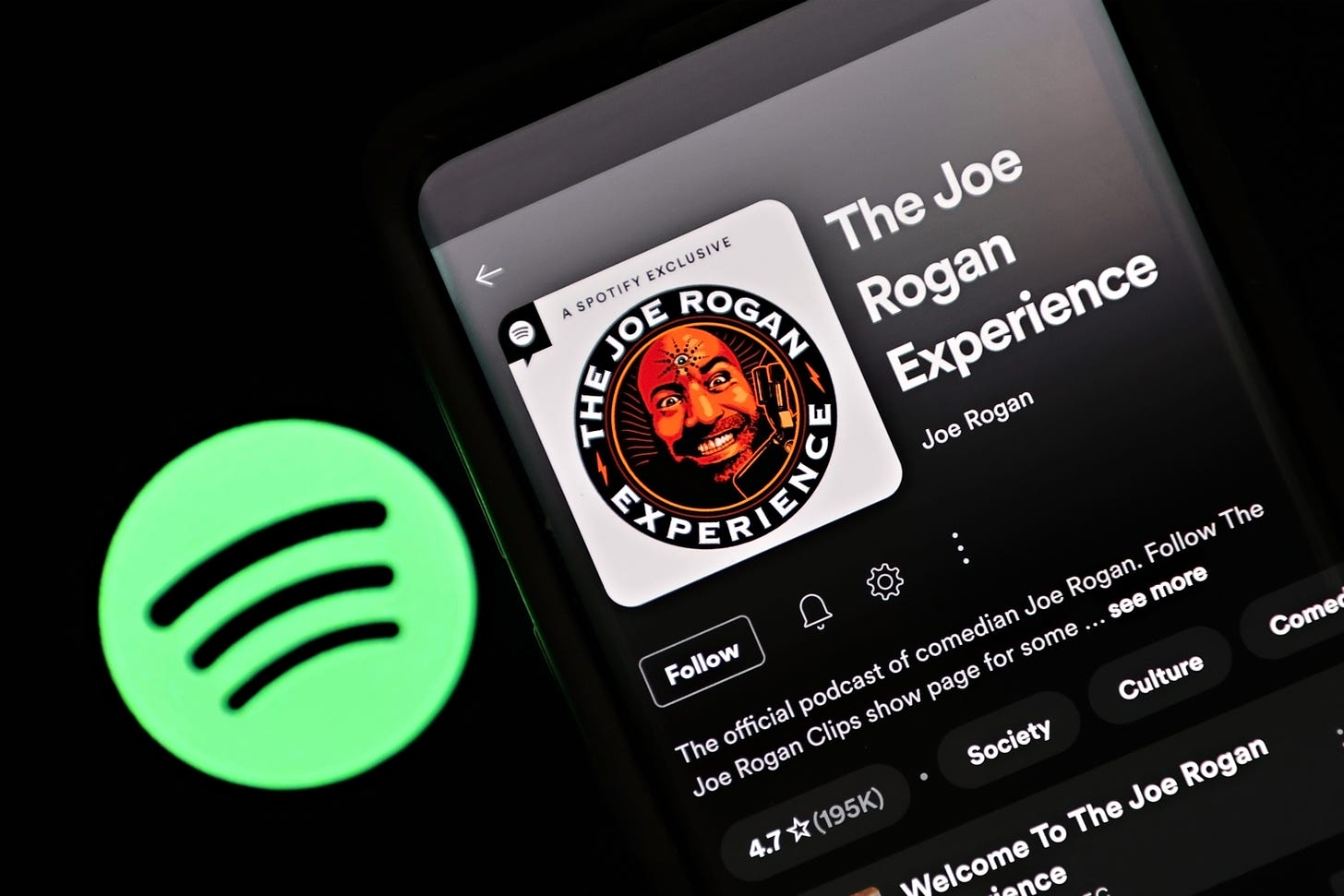 Photo illustration of the Spotify logo next to the Joe Rogan Experience podcast showing on a smartphone. (Cindy Ord / Getty Images)