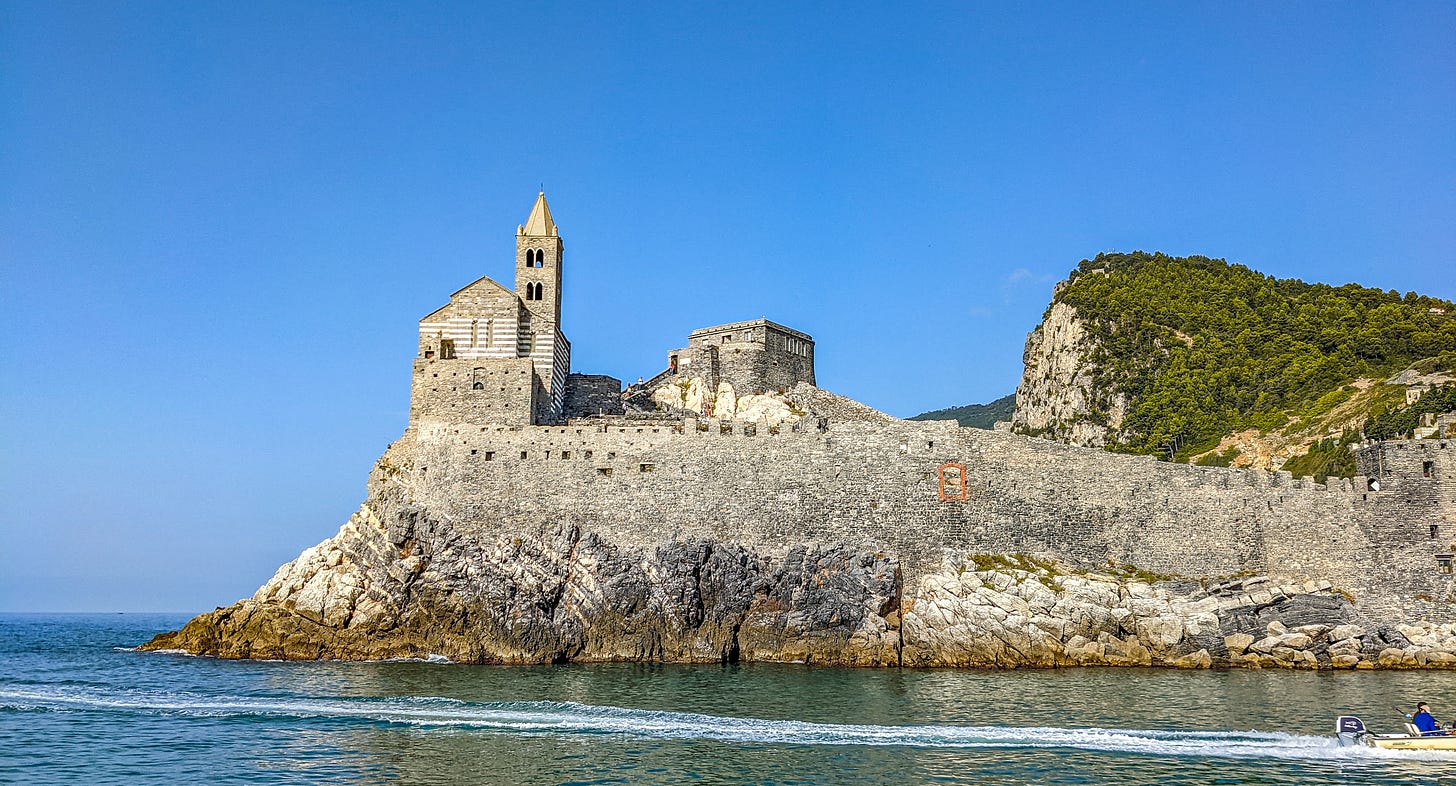 The Church of San Pietro standing on a rocky outcropping beneath a bright blue sky. 