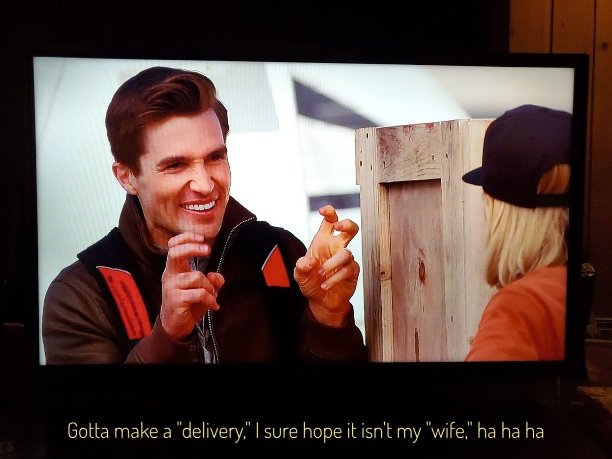 Jake laughing and making air quotes while standing next to a big wooden crate, captioned "gotta make a 'delivery,' I sure hope it isn't my 'wife,' ha ha ha"
