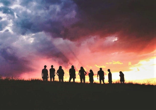 silhouette of group of people against colorful sunset sky