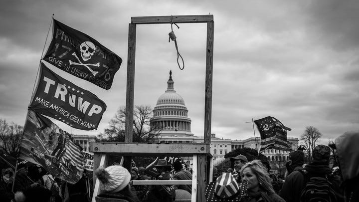 A crowd of Trump supporters surround a newly erected set of wooden gallows outside the Capitol Building.