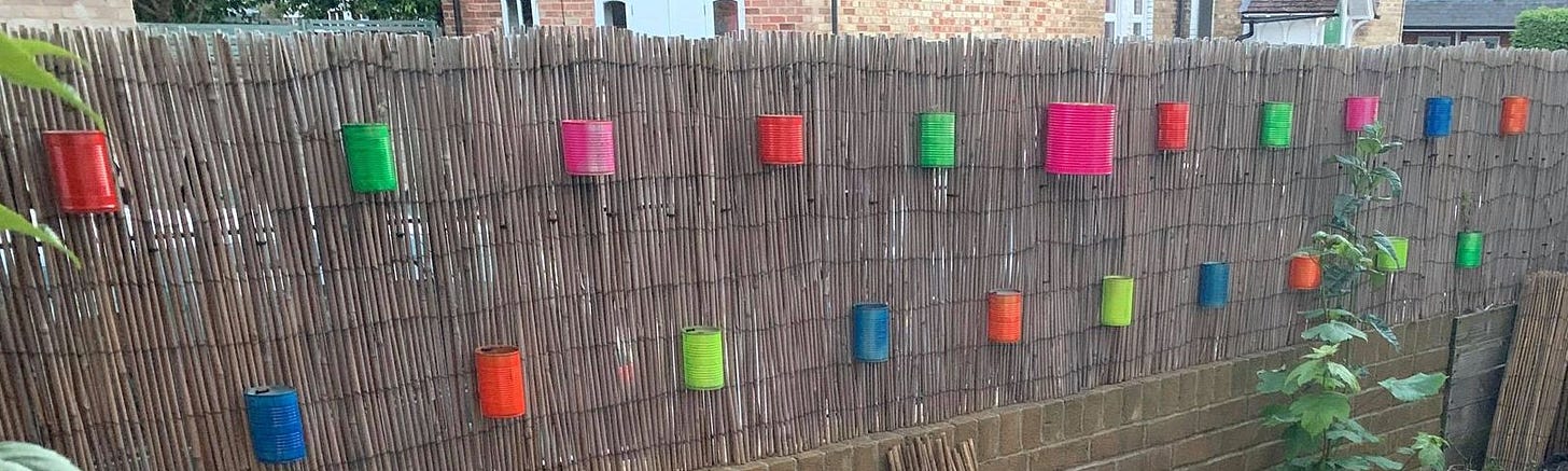 Brightly coloured spray-painted cans attached to an urban fence
