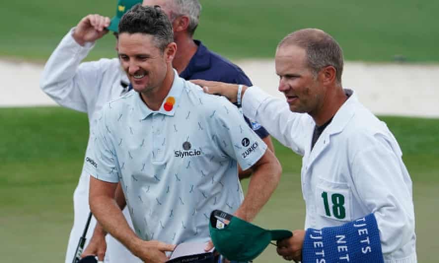 Justin Rose is congratulated by his caddie David Clark on the 18th green after an opening 65.