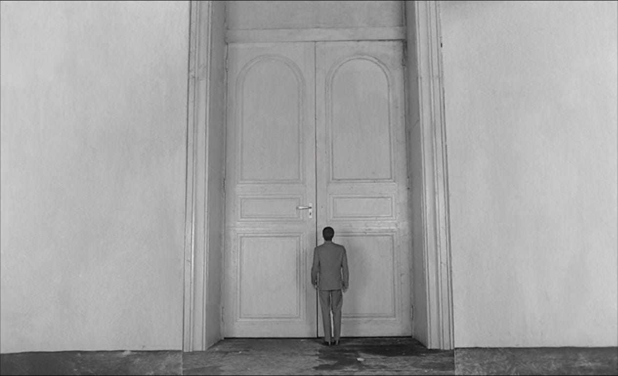 A man stands before door.