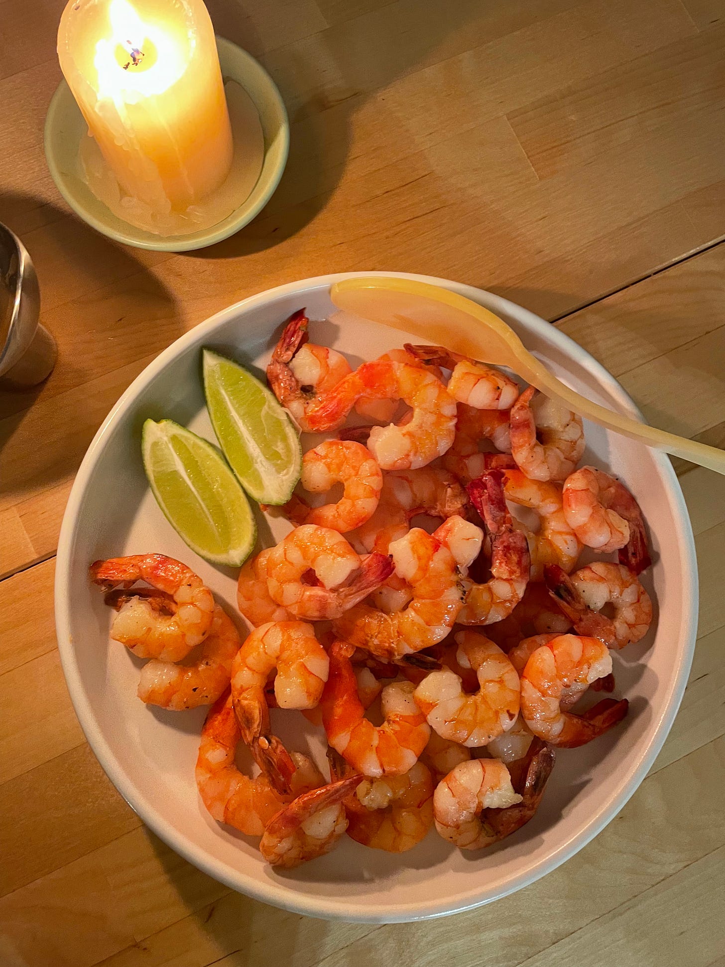 White plate of just baked honey prawns with lime juice for serving