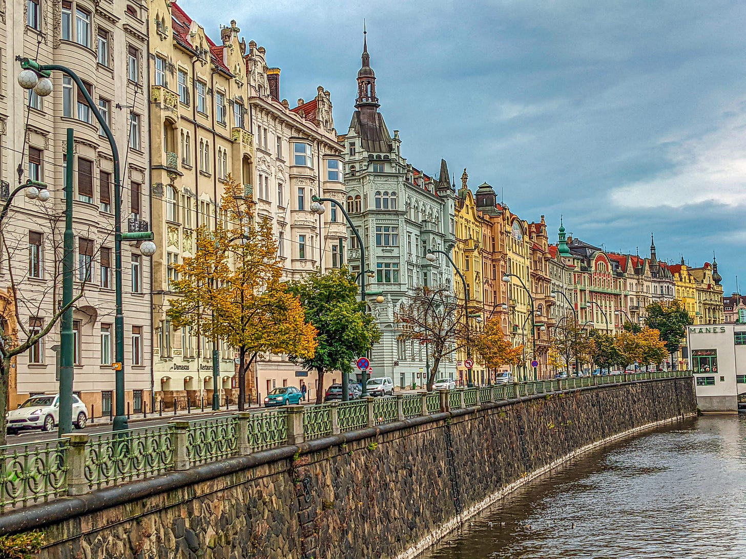 French-looking apartment buildings line a street at they overlook the Vltava River. 
