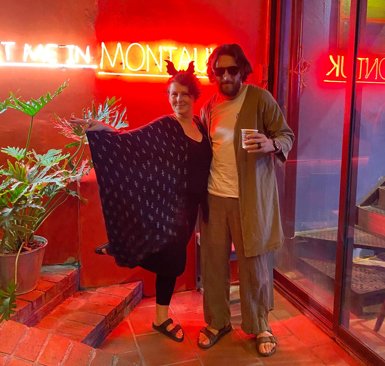 a woman dressed up as a bat stands with a man dressed up as Jeff Bridges from The Big Lebowski
