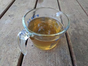 a measuring cup of strained spruce tip syrup